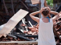 Recovering After A Fire: A Guide For Business Owners Woman standing in front of burned out house and holding her head with both hands