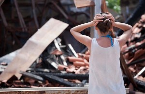 Recovering After A Fire: A Guide For Business Owners Woman standing in front of burned out house and holding her head with both hands